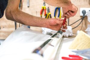 A man's hand screwing with a red screwdriver