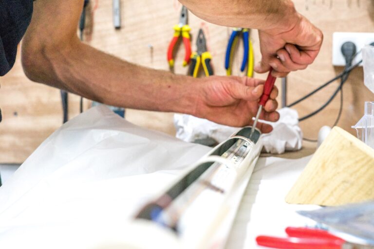 A man's hand screwing with a red screwdriver